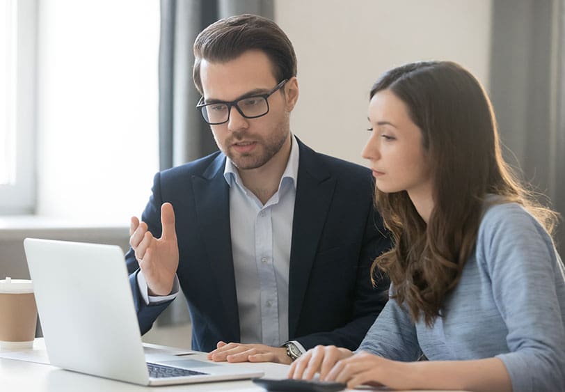 A man and woman are looking at a laptop.