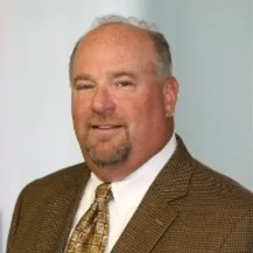 A man in a suit and tie standing next to a wall.